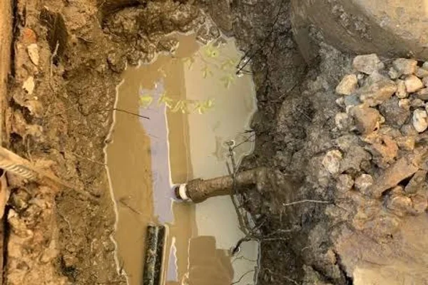 Excavated trench locating underground water supply line leak and connection in Salt Lake City