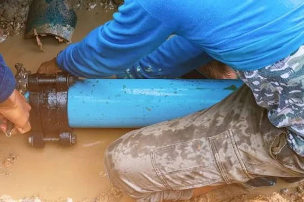 Plumbing technician installing heavy duty repair coupling on underground blue water line in Salt Lake City